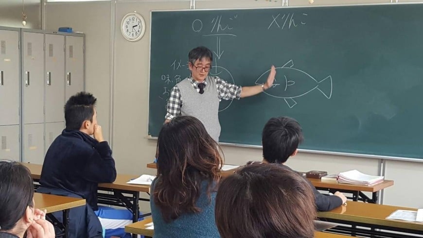 黒板の前で生徒たちに語りかけながら授業をする塾長